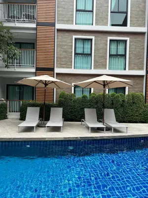 a pool with chairs and umbrellas next to a building at Seaside vacation in Rawai Beach