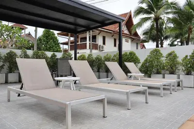 a row of white chairs and tables on a patio at Kamala - Chonlada Holiday Home 2 BR Residence in Kamala Beach
