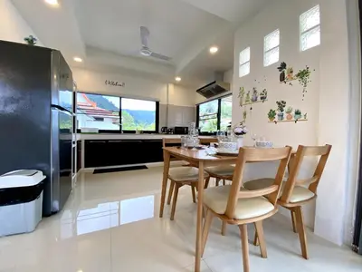 a kitchen with a table and chairs and a refrigerator at Kamala - Chonlada Holiday Home 2 BR Residence in Kamala Beach