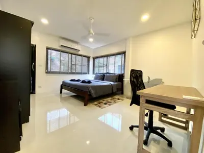a bedroom with a bed and a table in it at Kamala - Chonlada Holiday Home 2 BR Residence in Kamala Beach