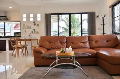a living room with a brown couch and a table at Kamala - Chonlada Holiday Home 2 BR Residence in Kamala Beach