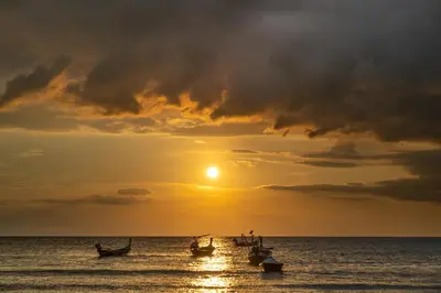 a group of boats in the ocean at sunset at Anodard Phuket, Nai Yang Beach in Thalang