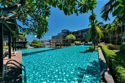 a swimming pool in a resort with palm trees and buildings at Pixel Condo - Panwa Beach in Ban Ao Makham