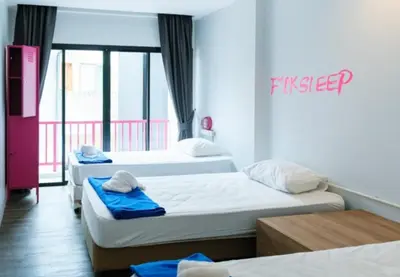 a room with three beds and a sign on the wall at Slumber Surf Phuket Kata in Kata Beach