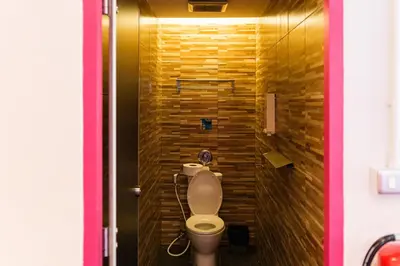 a bathroom with a toilet and a wooden wall at Slumber Surf Phuket Kata in Kata Beach