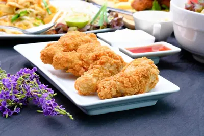 a plate of food with fried chicken on a table at Slumber Surf Phuket Kata in Kata Beach