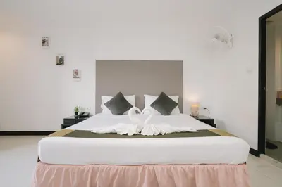 a large white bed with two white swans on it at Noble House Patong in Patong Beach