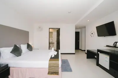a bedroom with a white bed and a flat screen tv at Noble House Patong in Patong Beach