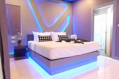 a bedroom with a bed with neon lights on it at I AM O'TEL Patong in Patong Beach