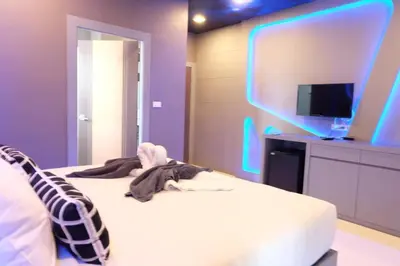 a bedroom with purple walls and a bed with a tv at I AM O'TEL Patong in Patong Beach
