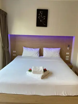 a large white bed with two towels on it at I AM O'TEL Patong in Patong Beach