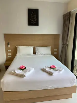 a bed with two towels and pink flowers on it at I AM O'TEL Patong in Patong Beach