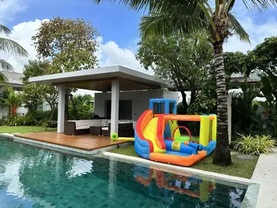 a pool with a inflatable water slide next to a house at Villa Jasmine - luxury private villa Bangtao Beach in Bang Tao Beach