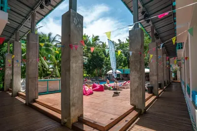 a deck with a pool with flags and people on the beach at Nomads Ao Nang Party Hostel 18-35 Years Old Only in Ao Nang Beach