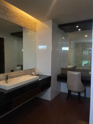a bathroom with a sink and a chair and a mirror at The Regent Bangtao Apartments in Bang Tao Beach