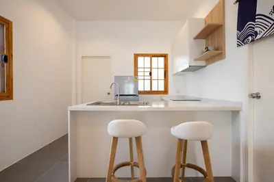 a kitchen with two white stools at a counter at Villa Sunrise Garden B190 in Thalang