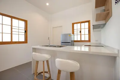 a kitchen with two white stools and a counter at Villa Sunrise Garden B191 in Thalang