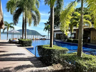 a swimming pool with palm trees and a resort at Spectacular Ocean View Apartment in Ban Saiyuan (1)
