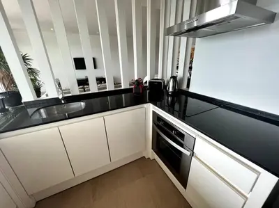 a kitchen with white cabinets and a black counter top at Spectacular Ocean View Apartment in Ban Saiyuan (1)