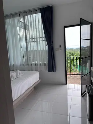 a bedroom with a bed and a large window at White Seaview Residence in Klong Muang Beach
