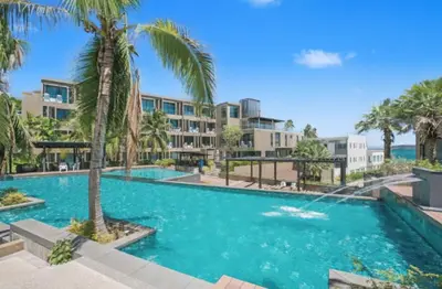 a swimming pool with palm trees and buildings at Pixels - Ocean Front Studio with Pool View Cape Panwa in Ban Ao Makham