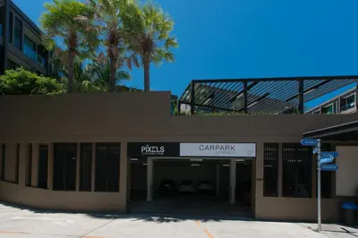 a building with a parking garage with palm trees at Pixels - Ocean Front Studio with Pool View Cape Panwa in Ban Ao Makham