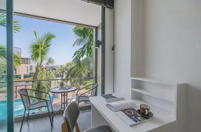 a room with a view of a balcony with a table and chairs at Pixels - Ocean Front Studio with Pool View Cape Panwa in Ban Ao Makham