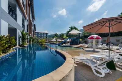 a pool at a hotel with chairs and a slide at Tuana Hotels Casa Del Sol in Kata Beach