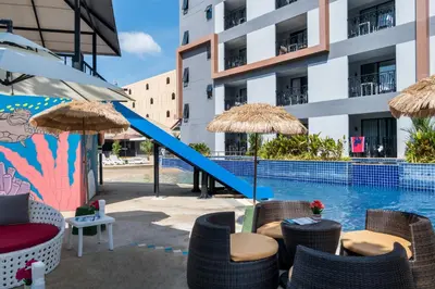 a swimming pool with chairs and umbrellas next to a building at Tuana Hotels Casa Del Sol in Kata Beach