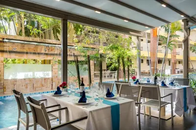 a dining room with tables and chairs and a pool at Tuana Hotels Casa Del Sol in Kata Beach