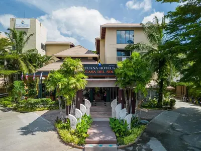 a building with palm trees in front of it at Tuana Hotels Casa Del Sol in Kata Beach