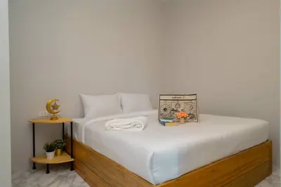 a bedroom with a bed with white sheets and a side table at Terminal 58 Airport in Ban Mut Dok Khao