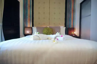a white bed with two stuffed animals on it at Palm Resort Krabi in Ban Ko Kwang