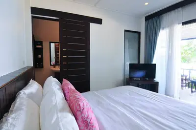 a bedroom with a bed with pink pillows and a television at Palm Resort Krabi in Ban Ko Kwang