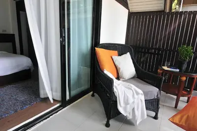 a balcony with a chair with an orange pillow on it at Palm Resort Krabi in Ban Ko Kwang
