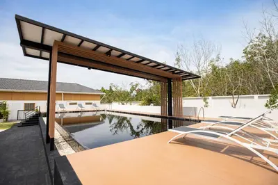 a swimming pool with a wooden table next to a house at Villa Sunrise Garden A181 in Thalang