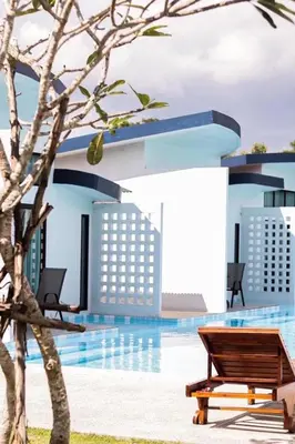 a bench next to a swimming pool with buildings at Blue Ba You Resort in Ban Khlong Haeng