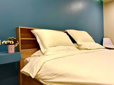 a bedroom with a white bed with a blue wall at THE NICE in Patong Beach