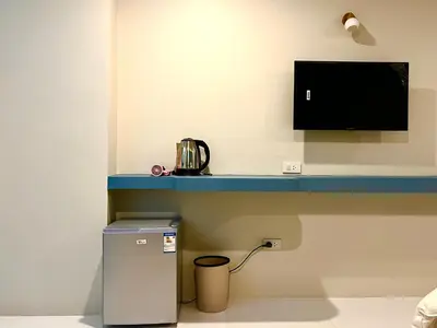 a room with a small refrigerator and a tv on a wall at THE NICE in Patong Beach
