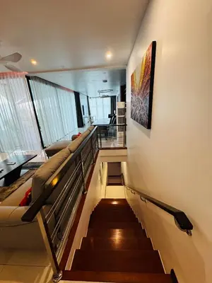 a staircase in a room with a couch and a painting at The Sunrise Ocean Villa 22 in Phuket Town
