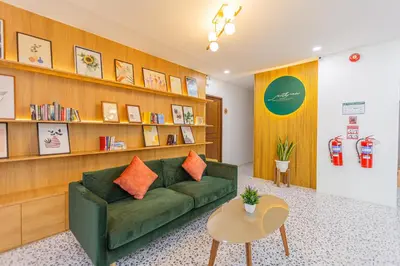 a living room with a green couch and a book shelf at South Siam Hotel in Phuket Town
