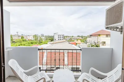 a balcony with white chairs and a view of a building at South Siam Hotel in Phuket Town