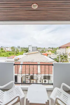 a balcony with white chairs and a view of a building at South Siam Hotel in Phuket Town