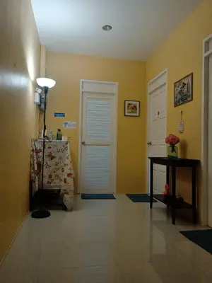 a hallway with yellow walls and a table and a door at 168Hostel Airport@Phuket in Thalang