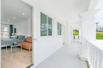 a living room with white walls and a couch at White House Apartment - Chalong in Chalong