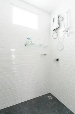 a white bathroom with a shower and a window at White House Apartment - Chalong in Chalong