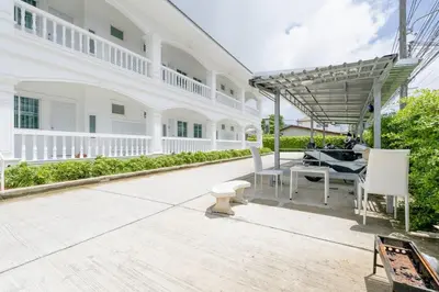 a patio of a white house with a table and chairs at White House Apartment - Chalong in Chalong