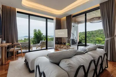 a living room with a large couch and large windows at VARANA Krabi Hotel in Klong Muang Beach