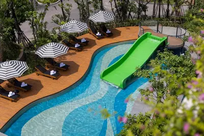 a swimming pool with a green slide and umbrellas at Anantara Koh Yao Yai Resort & Villas in Ko Yao Yai