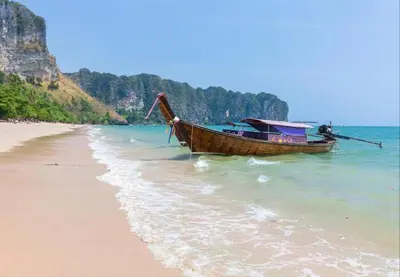 a boat sitting on the shore of a beach at CORNER SEA VIEW KRABI Ao Nang 4 STARS HOTEL RESIDENCE in Ao Nang Beach